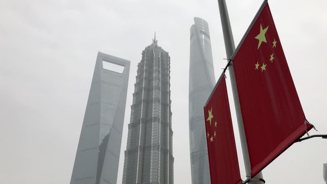 Shanghai, China - May 10, 2020: Chinese national flag & landmarks in downtown. Shanghai Tower, Jin Mao Tower and Shanghai World Financial Center. Flags on the street lamp in Lujiazui.