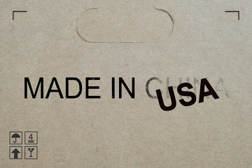 Shipment box with words 'Made in USA' replacing the fading word China. Concept for American government bringing manufacturing jobs back to US and decouple from China. America vs Chinese conflict.