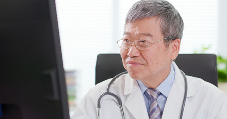 Senior male doctor look computer