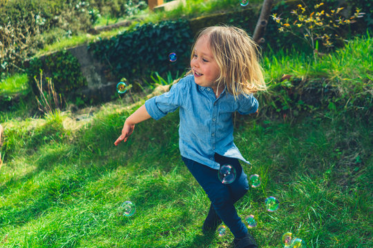 Preschooler chasing bubbles in the garden