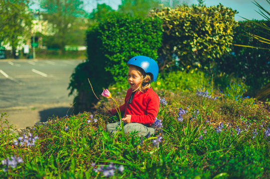 Preschooler wearing helmet sitting in flowerbed