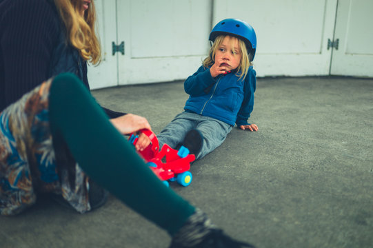 Mother helping her preschooler put on rollerskates