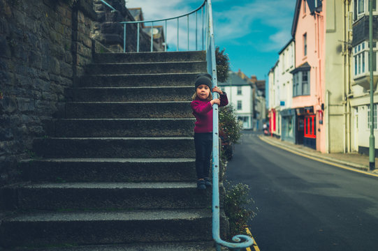 Preschooler standing on stairs in quiet small town