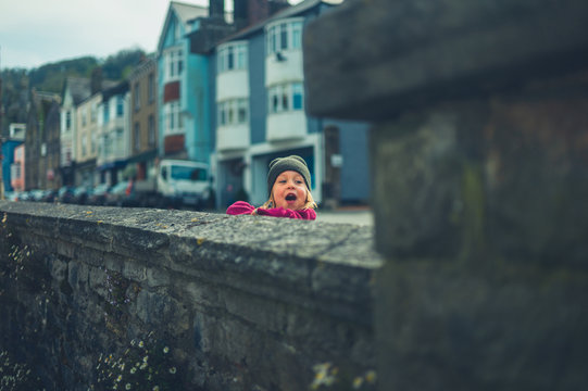 Preschooler looking over wall in small town