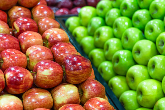 Assortment of many fresh ripe red and green apples displayed beautifully in a grocery store.