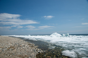 Natural background. Change of seasons.Baikal Lake in May morning.Spring landscape.The view from the rocks in the foreground of a snow-white fragments of ice floes. Northern nature
