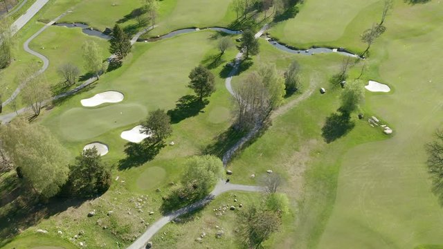 Aerial view of a golf course with bunkers, green grass & trees