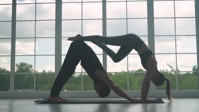 Wellness, man and woman do yoga together, perform stands and muscle stretching, joint training of a young couple.