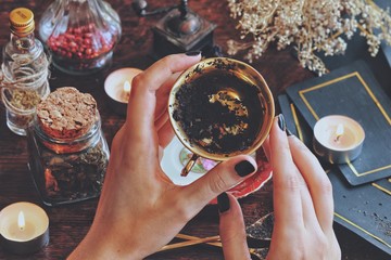 Wiccan witch holding a golden teacup for tea leaf scrying, divination, future reading. Black tea...