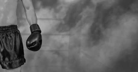 male boxer with black glove on boxing stage in dark foggy background, selective focused