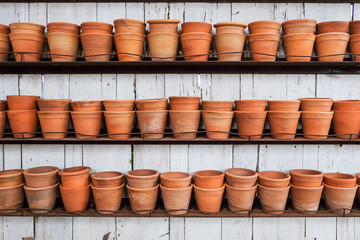 Fototapeta premium group of empty clay flower pots on a wooden shelf in a garden