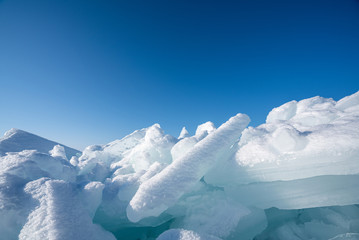 Closeup ice that covered with white snow. Water in the lake became frozen during winter period. Lake Baikal, Russia