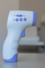 Thermometer Gun Isometric Medical Digital Non-Contact Infrared Sight Handheld Forehead Readings. Temperature Measurement Device with nursery in the background