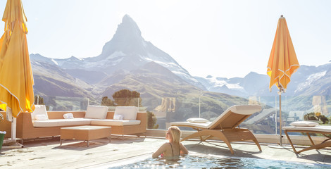Woman enjoying the panoramic view from the pool in the alps