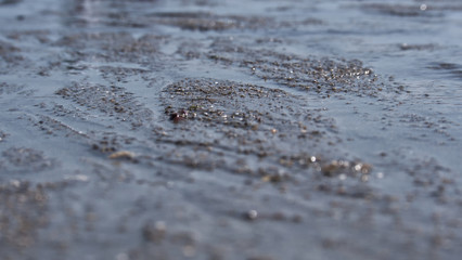 Sea water moving over a sandy beach on a warm sunny day