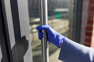 small business, pandemic and service concept - woman in protective glove trying to open closed office door