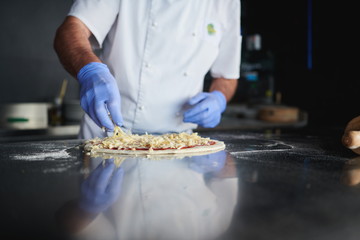chef  with protective coronavirus face mask preparing pizza