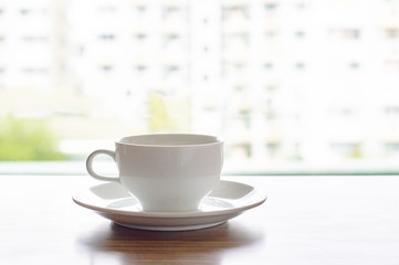white coffee cup on wood table with building background