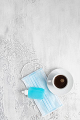 Cup of coffee, disposable face mask and hand sanitizer on light backround. New normality  concept. Top view .Copy space