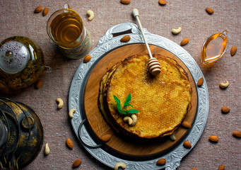 pancakes with honey and nuts on a wooden board and a tray. pancakes with tea.