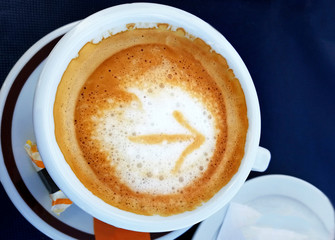 The arrow sign in a cup of coffee, in a coffee shop on the way of the Camino de Santiago