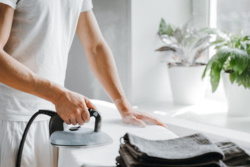 Man ironing bed linen on iron board with steam generator at home. Housework and household concept.