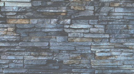Art technique design of unshaped Gray stone wall pattern.Stone cladding wall made of striped stacked slabs for background.
