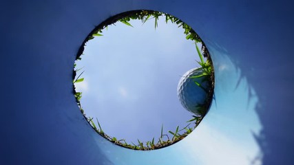 Hole in one successful putt. Golf ball going down hole with blue sky.  - Powered by Adobe