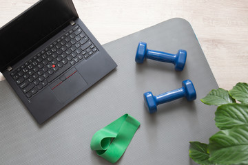 Two dumbbells for fitness at home and a laptop for remote training.