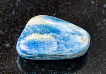 closeup of sample of natural mineral from geological collection - polished Kyanite rock on black granite background from Minas Gerais, Brasil
