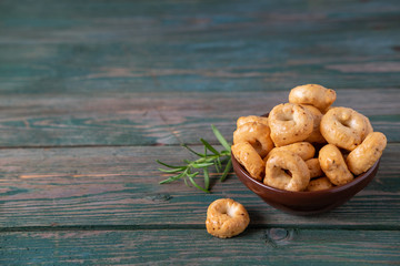 Traditional Italian snack tarallini, taralli in a ceramic bowl on a wooden background. Rustic style