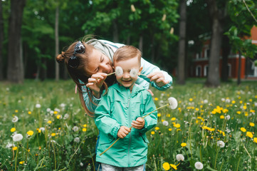 Mother and sons relationship, playing with dandelions in the park.