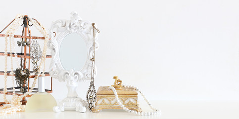 Fototapeta na wymiar Image of white vintage mirror and pearls over wooden table. For mockup, can be used for photography montage