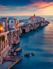 Iconic evening cityscape of Vieste - coastal town in Gargano National Park, Italy, Europe. Gorgeous spring sunset on Adriatic sea. Traveling concept background.