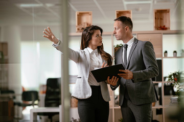 Colleagues in office. Businesswoman and businessman discussing work in office.	