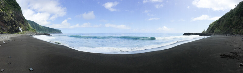 180 degree empty black sand beach view. Sea water light splash after sunset.