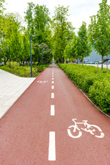 Sustainable transport. Blue road sign or signal of bicycle lane, road bike with green trees and nature background, vertical