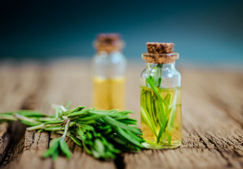 Top view Bottle glass of essential rosemary oil with rosemary on wooden rustic background. herbal oil concept