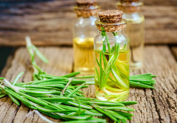 rosemary essential oil on a rustic wooden background. Herbal oil concept