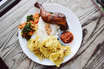 Grilled honey chicken rice with peanut chips and vegetables with spicy chili sauce. Traditional Indonesian food.
