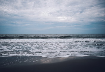Fototapeta na wymiar Small wavess on the beach with black sand. West Sumatra, Indonesia