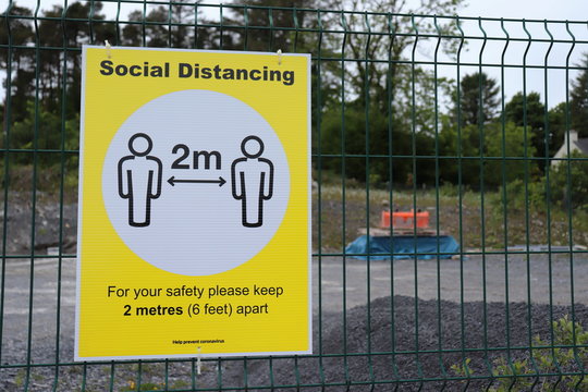 social distancing sign hangin on a building site fence