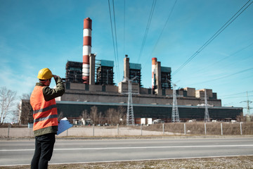 Obraz premium A young engineer in work equipment,controls the progress of work in a thermal power plant