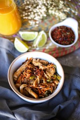udon noodles with chicken and vegetables, orange juice, lime and spices on light table