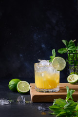Freshness tropical lemonade with lime, orange and mint on black. Vertical format.