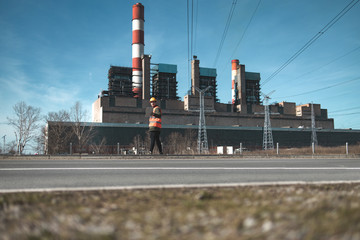 A young engineer in work equipment,controls the progress of work in a thermal power plant