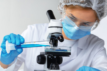 Scientist's hands doing chemical research with the help of microscope