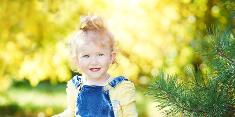 Beautiful little girl smiling. Look not at the camera. Park outside the house. Advertising photo. Positive child after quarantine. End lockdown. Horizontal banner. Copyspace