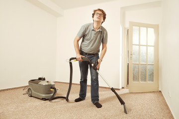Fototapeta na wymiar Caucasian man cleaning deeply carpet with wet cleaning machine