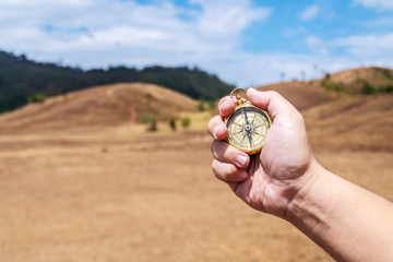Male traveler man hand with compass on background of meadow mountains in summer